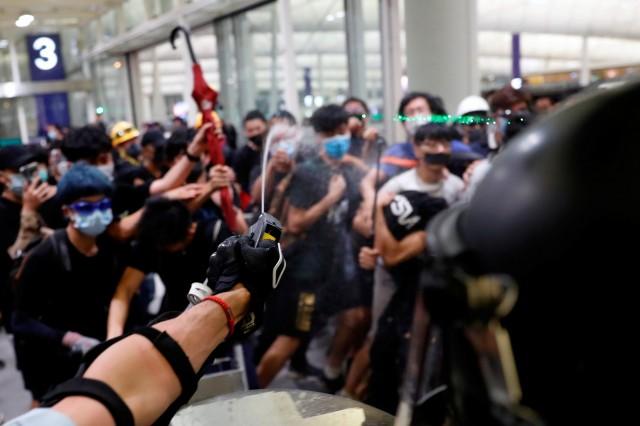 Riot police use pepper spray to disperse anti-extradition bill protesters during a mass demonstration after a woman was shot in the eye, at the Hong Kong international airport, in Hong Kong, China, August 13, 2019. REUTERS/Tyrone Siu