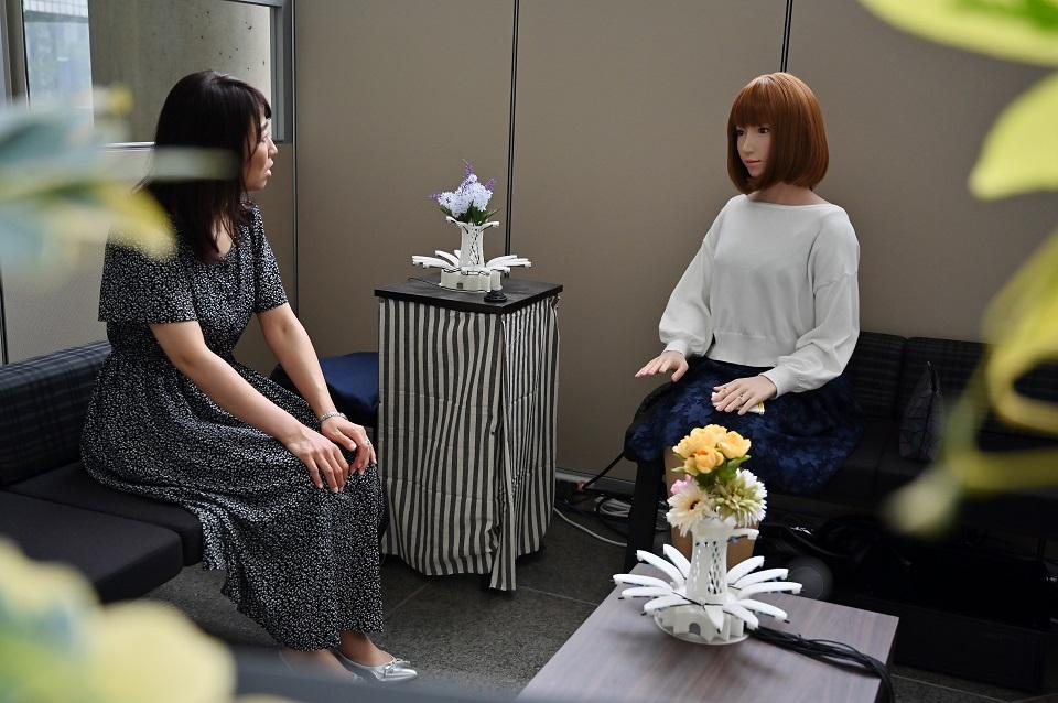 This photo taken on June 16, 2019 shows an assistant for robotician Hiroshi Ishiguro "talking" with a robot at the research center in Osaka. At a secretive research institute in western Japan, Ishiguro is fine-tuning technology that could blur the line between man and machine. Charly Triballeau/AFP