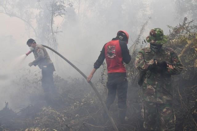 Indonesian firefighters spray water to extinguish a fire in Kampar on September 16, 2019. The number of blazes in Indonesia's rainforests has jumped sharply, satellite data showed on September 12, spreading smog across Southeast Asia and adding to concerns about the impact of increasing wildfire outbreaks worldwide on global warming