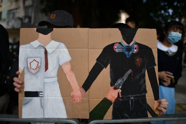 A protester holds up artwork depicting student Tsang Chi-kin, 18, being shot in the chest by police during violent pro-democracy demonstrations on China's October 1 National Day, during a protest at a school in Hong Kong on October 2, 2019. Hundreds of Hong Kongers staged a sit-in on October 2 outside the school. Mohd Rasfan/AFP