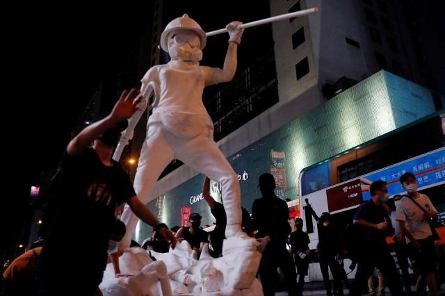 The statue depicts a female protester in a gas mask, protective goggles and helmet, an umbrella in one hand and a black flag in the other, proclaiming the protest slogan "Liberate Hong Kong, revolution of our times." It is seen here during a demonstration after a government&acirc;s ban on face masks under emergency law, at Mong Kok, October 4, 2019. REUTERS/Tyrone Siu