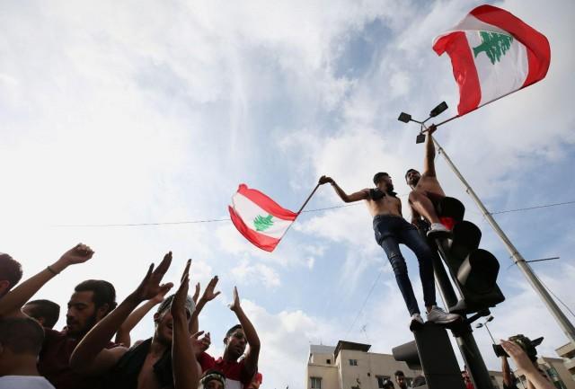 Demonstrators carry national flags and gesture during a protest targeting the government over an economic crisis in the port city of Sidon, Lebanon October 18, 2019. REUTERS/Ali Hashisho