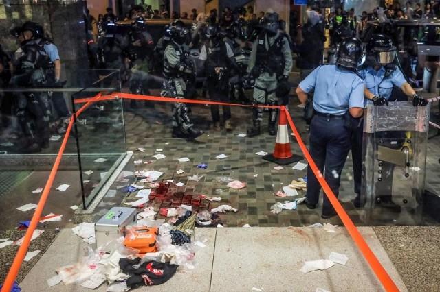 Blood and debris are seen on the ground at the entrance of a shopping mall as riot police secure the scene after a bloody knife fight broke out in Hong Kong on November 3, 2019. A bloody knife fight in Hong Kong left six people wounded on November 3 evening, including a local pro-democracy politician who had his ear bitten off, capping another chaotic day of political unrest in the city. Vivek Prakash/AFP