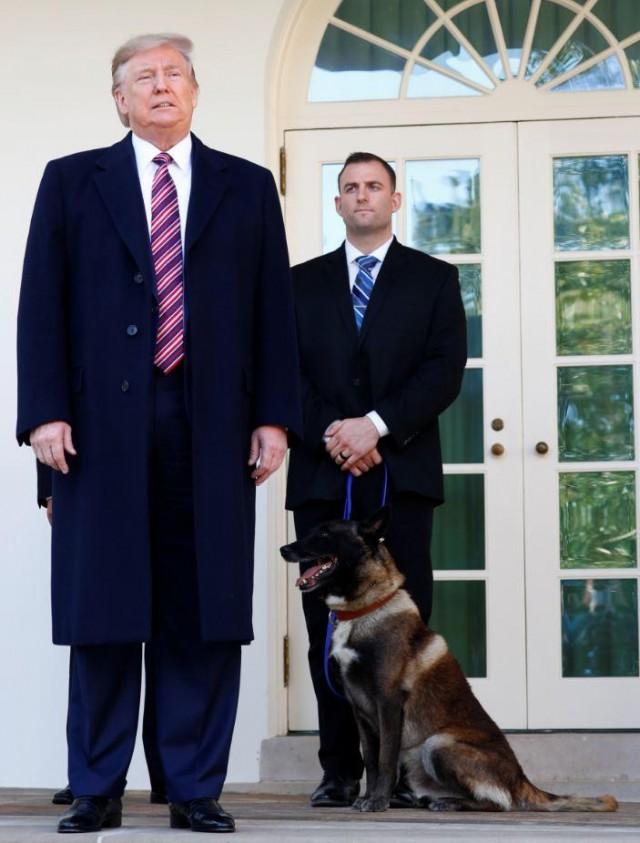 US President Donald Trump poses with Conan, the US military dog that participated in and was injured in the US raid in Syria that killed ISIS leader Abu Bakr al-Baghdadi, while standing with the dog's military handler on the colonnade of the West Wing of the White House in Washington, US November 25, 2019. REUTERS/Tom Brenner