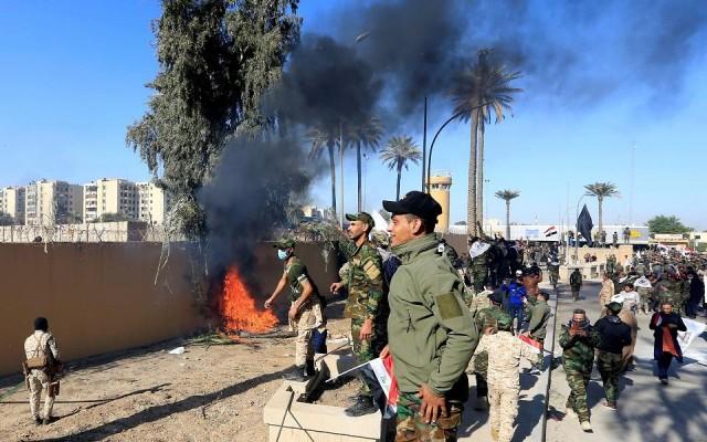 Hashd al-Shaabi (paramilitary forces) fighters set the US Embassy wall on fire as they protest to condemn air strikes on their bases, in Baghdad, Iraq December 31, 2019. REUTERS/Thaier al-Sudani