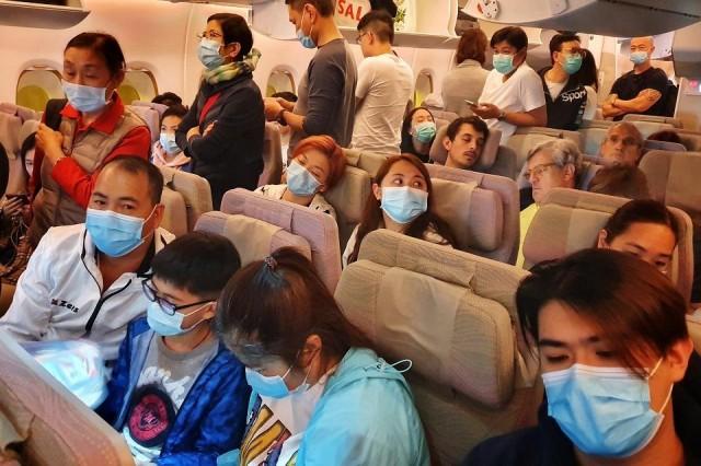 This picture taken on January 23, 2020 shows passengers wearing masks prepare to disembark from a flight from Hong Kong on arrival at Bangkok's airport on January 23, 2020. Vivek Prakash/AFP