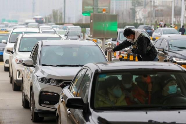 A staff member from a local sanitation and epidemic prevention team checks body temperature of a passenger in a car at a toll station in Wuhan, Hubei province, China January 23, 2020. China Daily via REUTERS 