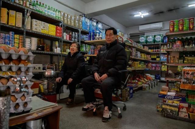 Owner Kim Kyung-soon (L) sits in the Pig Rice supermarket in Seoul on February 13, 2020. 