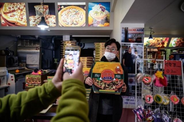 A customer poses before a photo of film director Bong Joon-ho at the 'Sky Pizza' restaurant in Seoul on February 13, 2020.