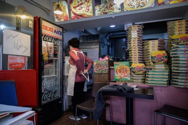 A signed message written by film director Bong Joon-ho is displayed (L) as pizza restaurant owner Eom Hang-ki, 65, works in her restaurant 'Sky Pizza' in Seoul on February 13, 2020. ED JONES/ AFP