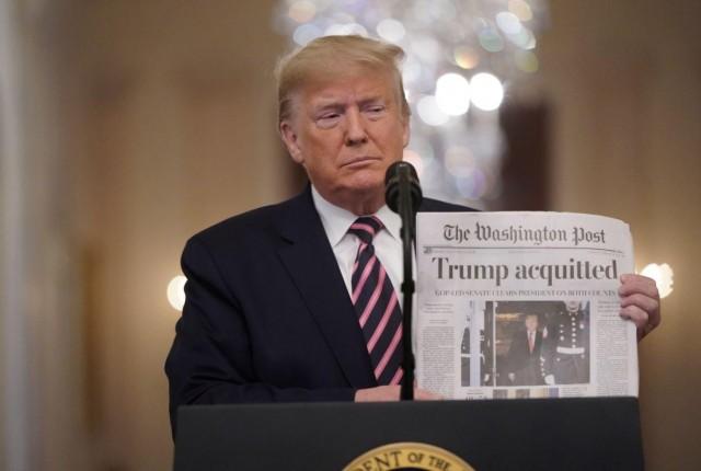 US President Donald Trump holds up a copy of the Washington Post's front page showing news of Trump's acquittal in his Senate impeachment trial, as he arrives to deliver a statement about his acquittal in the East Room of the White House in Washington, U.S., February 6, 2020. REUTERS/Joshua Roberts