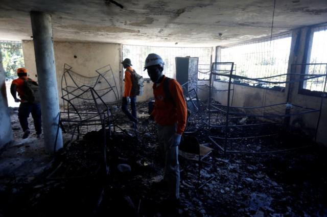 Civil protection workers stand inside a bedroom at an orphanage after it was destroyed in a fire, in Port-au-Prince, Haiti, February 14, 2020. REUTERS/Jeanty Junior Augustin