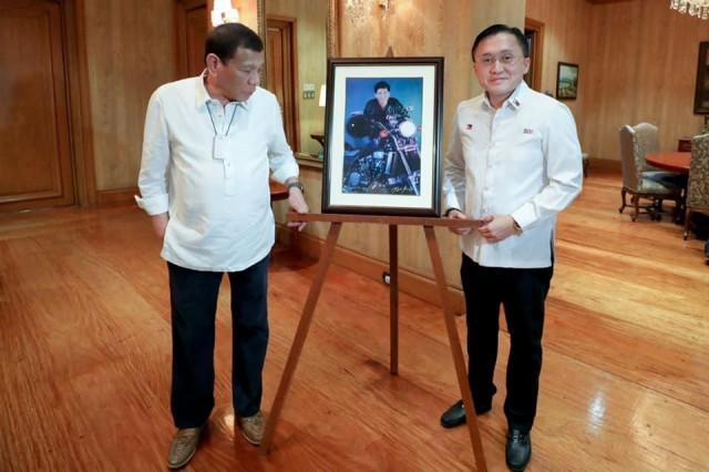 President Rodrigo Duterte checks with the picture of himself on a motorbike with Sen. Christopher "Bong" Go. PHOTO FROM SEN. CHRISTOPHER "BONG" GO