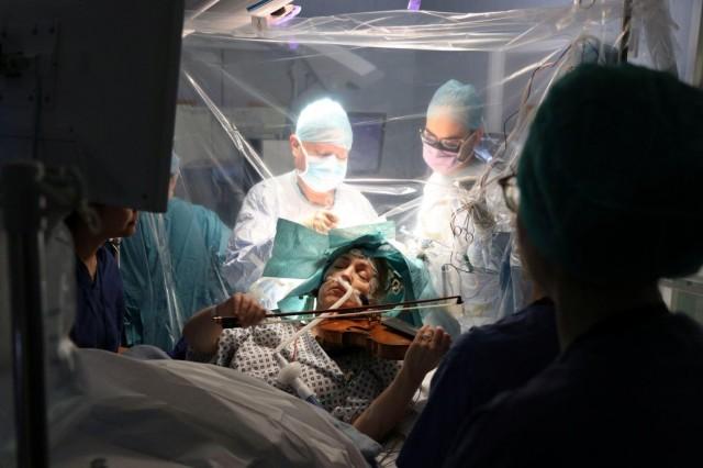 A patient, 53-year-old Dagmar Turner plays violin while surgeons remove her brain tumor at King's College Hospital in London, Britain, January 31, 2020 in this handout image obtained by Reuters on February 19, 2020. King's College Hospital/Handout via REUTERS