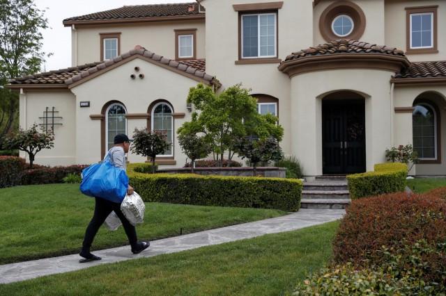 Excelso Sabulao, a 35-year-old independent contract delivery driver for Amazon Flex, carries deliveries to a house, as spread of the coronavirus disease (COVID-19) continues, in Dublin, California, U.S., April 6, 2020. Picture taken April 6, 2020. REUTERS/Shannon Stapleton