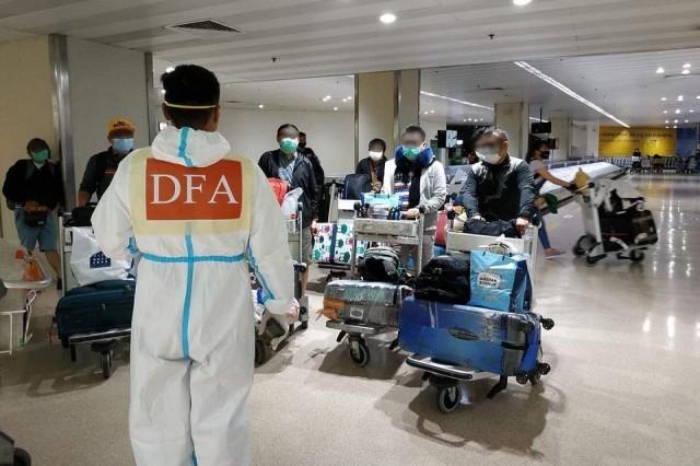 A DFA employee guides repatriated OFWs from Indonesia at NAIA Terminal 1 on Sunday, APril 12, 2020. Photo: DFA-OUMWA