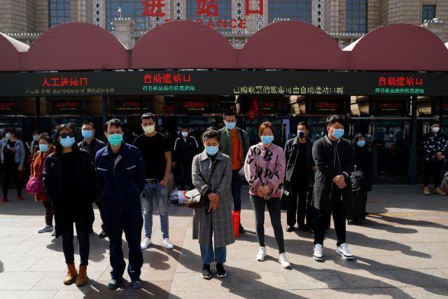 People wearing face masks stand to pay tribute as China holds national mourning for those who died of the coronavirus disease (COVID-19), on the Qingming tomb-sweeping festival, in Beijing April 4, 2020. REUTERS/Thomas Peter