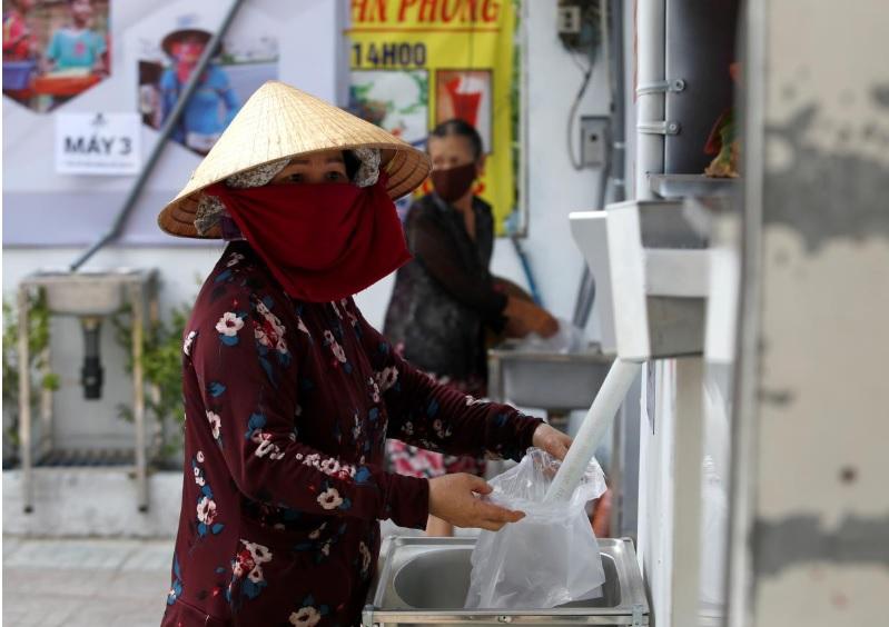 A woman fills a plastic bag with rice from a 24/7 automatic rice dispensing machine 'Rice ATM' during the outbreak of the coronavirus disease (COVID-19), in Ho Chi Minh, Vietnam, April 11, 2020. REUTERS/Yen Duong
