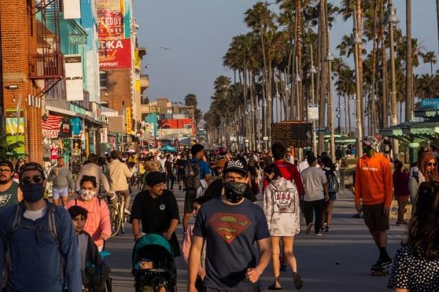 People walk at the boardwalk in Venice Beach during the first day of the Memorial Day holiday weekend amid the novel coronavirus pandemic in California on May 23, 2020. Los Angeles County officials announced May 22 that beach bike paths and some beach parking lots would reopen and curbside service at indoor malls would be permitted. The county reopened its beaches a week ago but kept beach parking lots, bike paths, piers and boardwalks closed. Apu Gomes/AFP