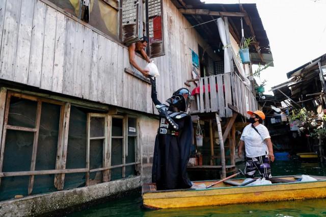 A village officer dressed as the Star Wars character Darth Vader rides a small boat to deliver relief goods to residents in the flooded Artex Compound in Malabon, Metro Manila, May 4, 2020. REUTERS/Eloisa Lopez 