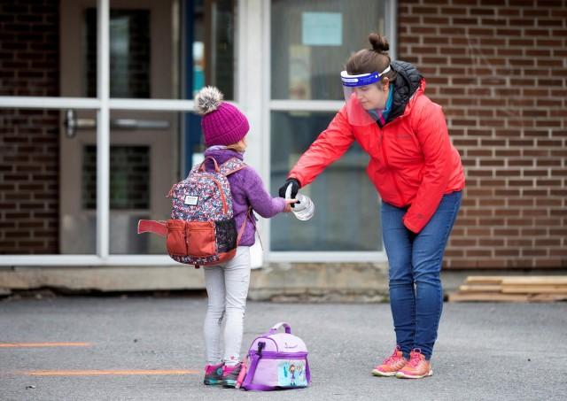 A student has her hands sanitized in the schoolyard, as schools outside the greater Montreal region begin to reopen their doors amid the coronavirus disease (COVID-19) outbreak, in Saint-Jean-sur-Richelieu, Quebec, Canada May 11, 2020. REUTERS/Christinne Muschi