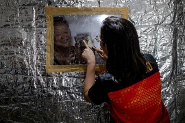 Jan Claire Dorado, 30, a doctor assigned to the coronavirus disease (COVID-19) Emergency Room of East Avenue Medical Center, bonds with her mother and cat from behind the small plastic window on her makeshift isolation room to protect her family from potential exposure to the coronavirus disease (COVID-19), in Quezon City, June 26, 2020. REUTERS/Eloisa Lopez