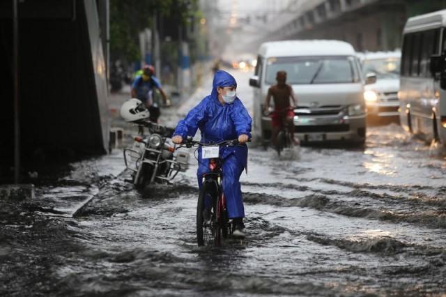 Cyclists ride through gutter-deep flood waters on Taft Avenue in Manila due to a sudden downpour on Thursday, June 11, 2020. The National Capital Region remains under a general community quarantine against the COVID-19 pandemic. DANNY PATA