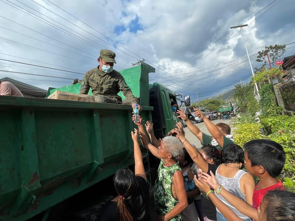 Residents in Bohol flock to a truck as a soldier hands water bottles and food items on Sunday, December 19, 2021. Typhoon Odette caused devastation in Bohol, and supplies are running low. IAN CRUZ