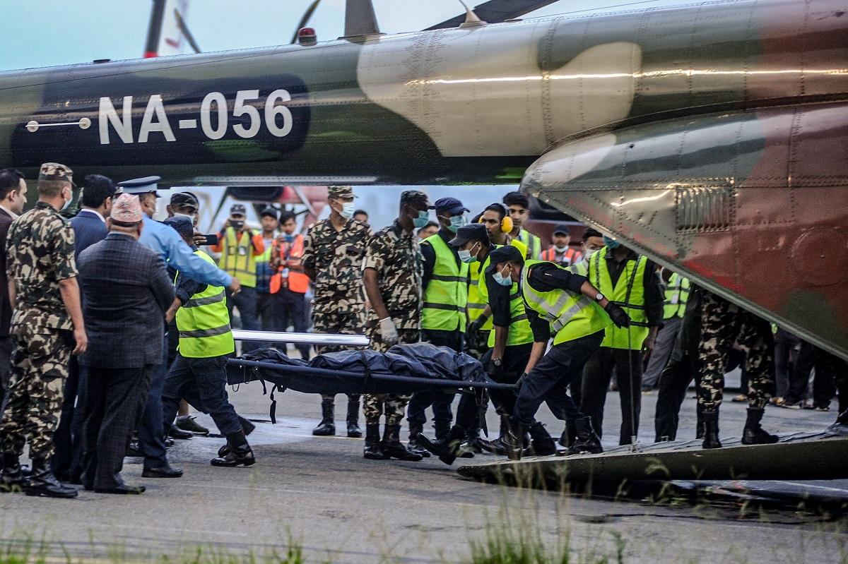 Nepalâ€™s security personnel carry the bodies of victims of a crash of a Twin Otter aircraft operated by Tara Air that crashed earlier in the Himalayas with 22 people on board, brought to Kathmandu on an army helicopter at Tribhuvan International Airport in Kathmandu on May 30, 2022. Bikash Karki/ AFP