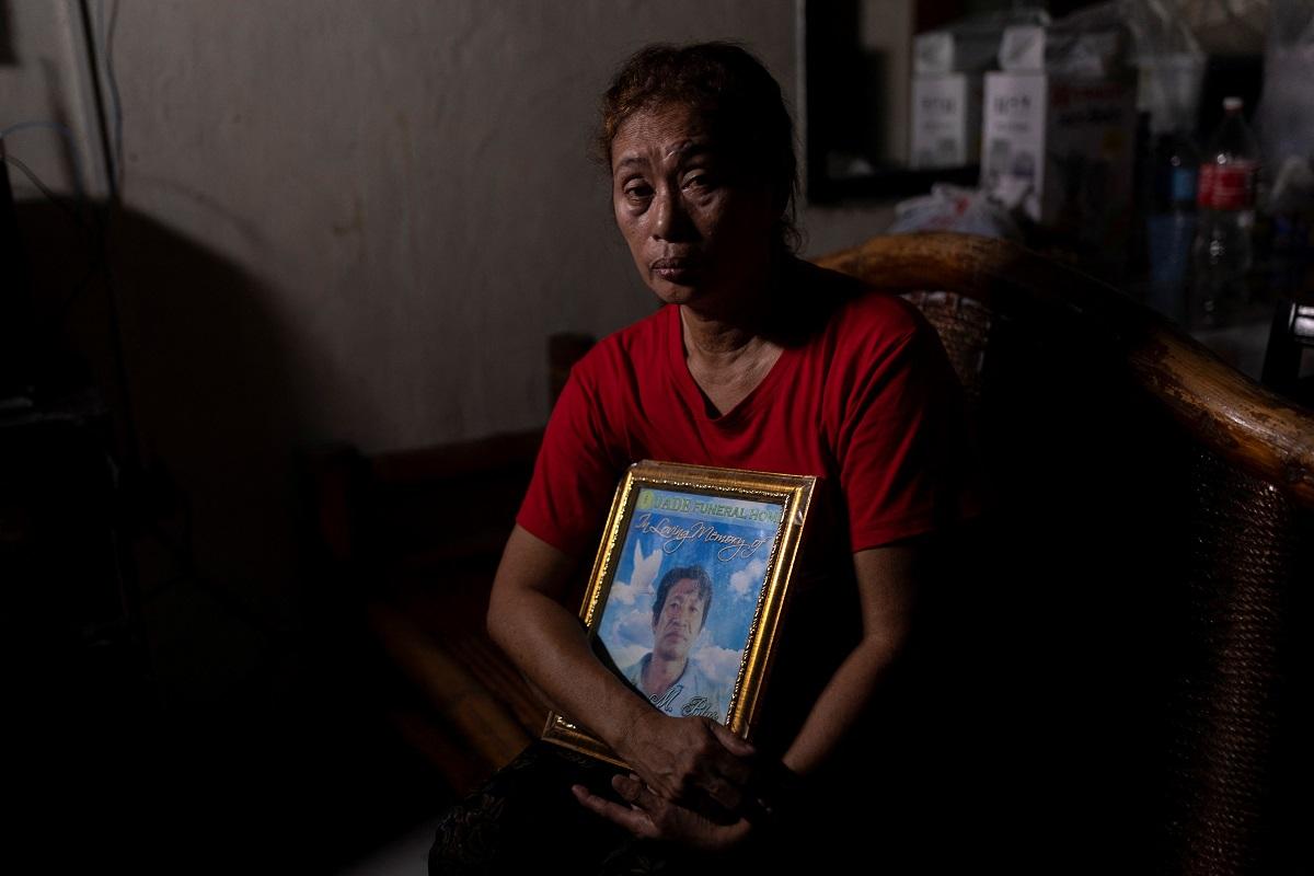 Aurora Blas holds a portrait of her husband Thelmo Blas in her home in Caloocan City, Philippines, April 1, 2021. A police report says Blasâ€™ body was dumped by the side of the road in 2016 along with a placard calling him a drug pusher. His death certificate says he died of pneumonia. REUTERS/Eloisa Lopez