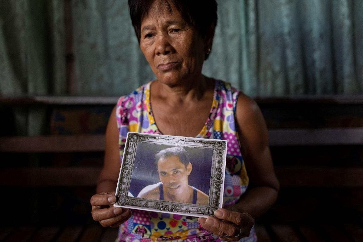 The mother of Erwin Garzon, a drug war victim, holds his portrait in her home in Caloocan City, March 9, 2022. REUTERS/ Eloisa Lopez