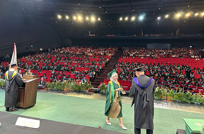One of the new FEU graduates receiving her diploma