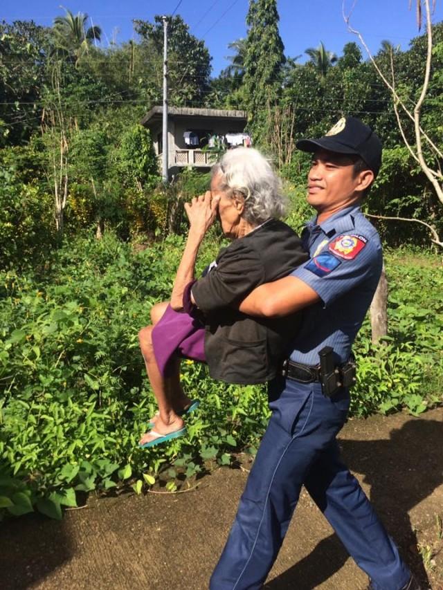 Buhat-buhat ni PO1 Rogel Mazo si Enocencia F Ferolino, 89, dahil hirap ito maglakad. PHOTO BY Calatrava Municipal Police Station