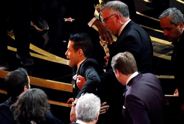 Best Actor winner Rami Malek is helped up after falling down the stairs on the stage. REUTERS/Mike Blake
