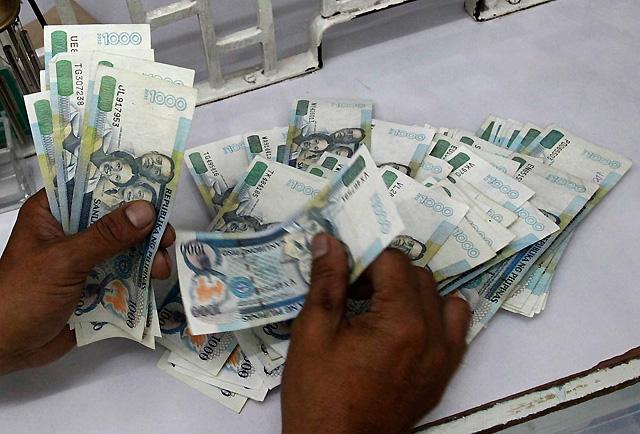 Money changer counts P1,000 bills in Manila