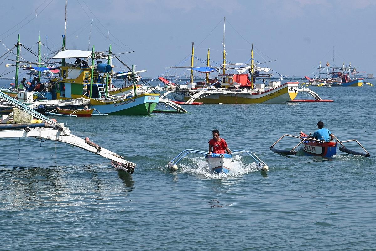 Sur cette photo prise le 20 août 2022, l'équipage sur des stabilisateurs passe devant la pêche "mère" bateaux à Barangay Cato, ville d'Infante, province de Pangasinan, alors qu'ils se préparent à partir pour une expédition de pêche à Scarborough Shoal.  Ted Aljibe / AFP