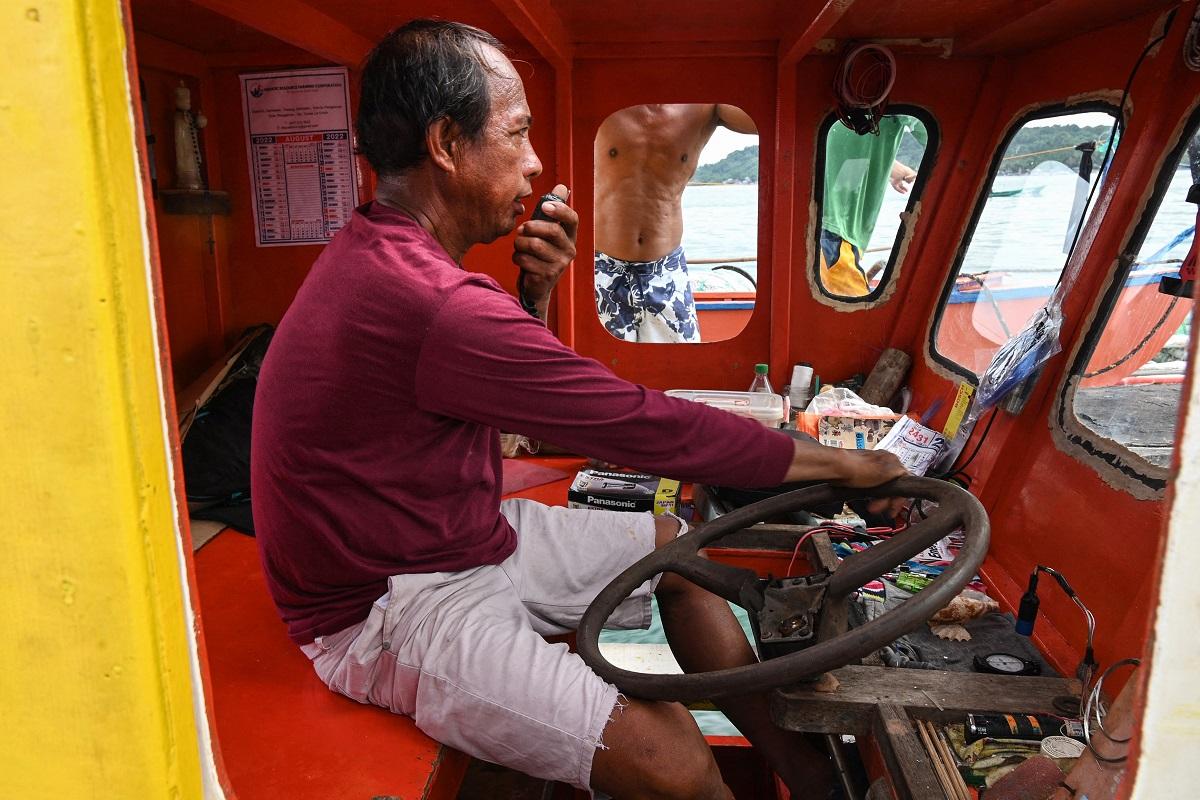 Sur cette photo prise le 11 août 2022, le pêcheur Christopher de Vera parle sur une radio bidirectionnelle avec d'autres pêcheurs à l'intérieur de leur lieu de pêche "mère" bateau à Barangay Cato, ville d'Infante, province de Pangasinan, alors qu'ils se préparent à partir pour une expédition de pêche à Scarborough Shoal.  Ted Aljibe / AFP