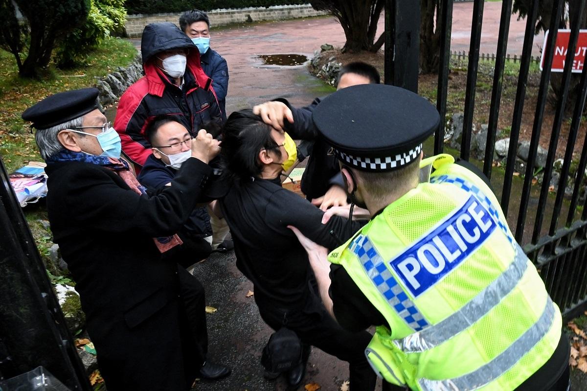 This handout from The Chaser News taken on October 16, 2022 and released to AFP on October 17 shows an incident involving a scuffle between a Hong Kong pro-democracy protester (C) and Chinese consulate staff, as a British police officer attempts to intervene, during a demonstration outside the consulate in Manchester. UK police said on October 17 they were probing the reported beating of a Hong Kong pro-democracy protester in the grounds of the Chinese consulate in Manchester, northern England. Matthew Leung/ The Chaser News/ AFP