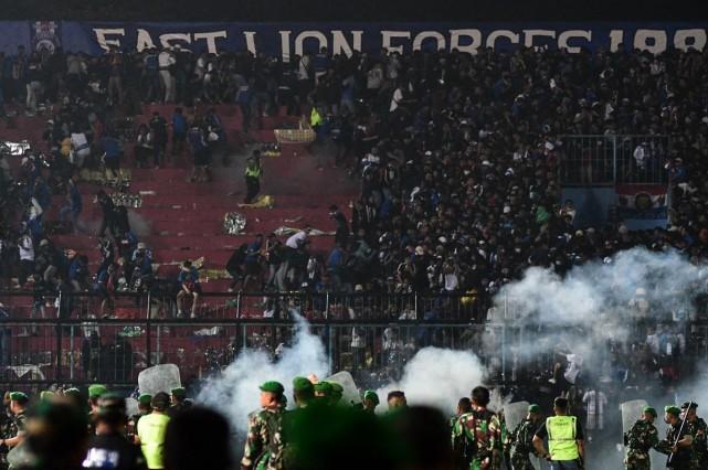 This picture taken on October 1, 2022 shows security personnel (lower) on the pitch after a football match between Arema FC and Persebaya Surabaya at Kanjuruhan stadium in Malang, East Java. Fans invaded the pitch and police responded with tear gas, triggering a deadly stampede, officials said. Str/AFP