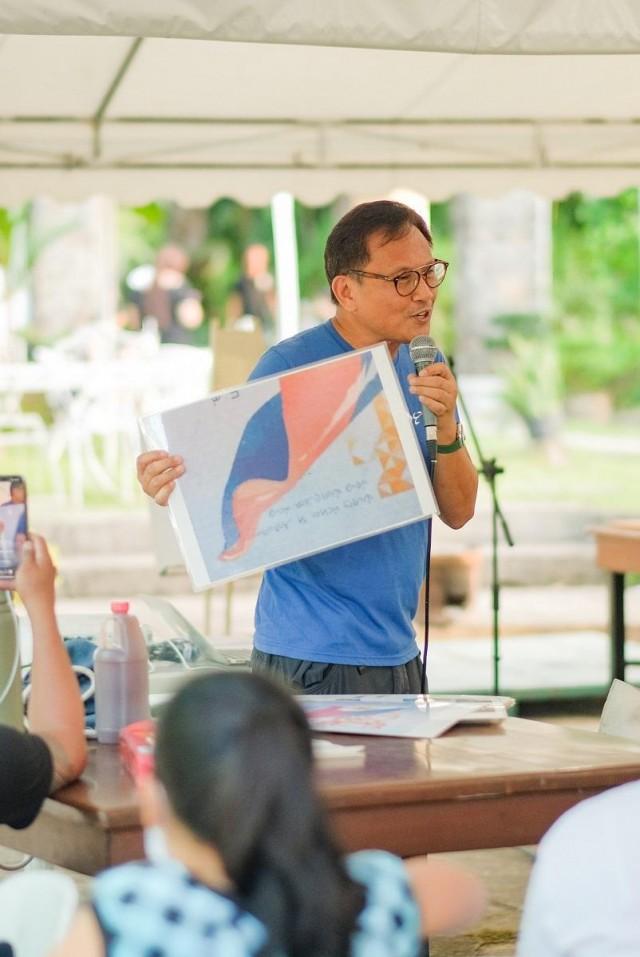 Howie giving a Baybayin workshop in Silay, Negros Occidental earlier this year. Heâ€™s holding a blown-up page in the Philippine passport that contains a proverb written in Baybayin. 