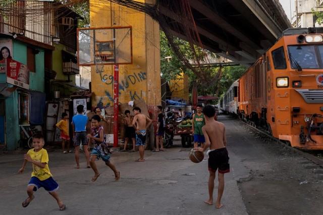 Boys play basketball as a train passes by in Pandacan, Manila, May 30, 2023. REUTERS/Eloisa Lopez