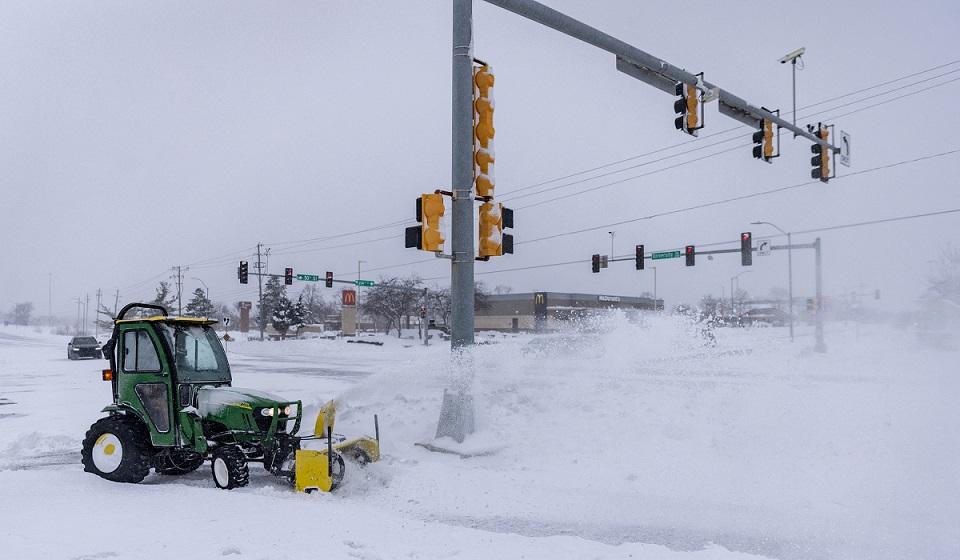 Worker blows snow from the sidewalk after a blizzard in West Des Moines, Iowa