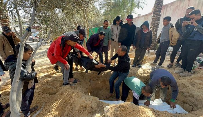 People bury bodies of Palestinians killed in an Israeli strike, at the Nasser Hospital