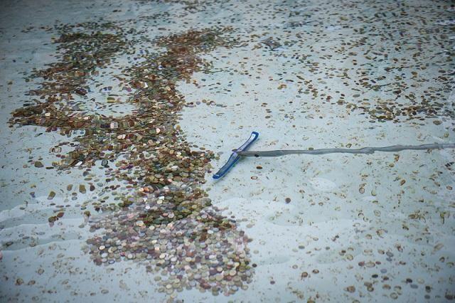 A broom is used to gather coins from the Trevi Fountain in Rome, Italy, February 19, 2024. REUTERS/ Guglielmo Mangiapane