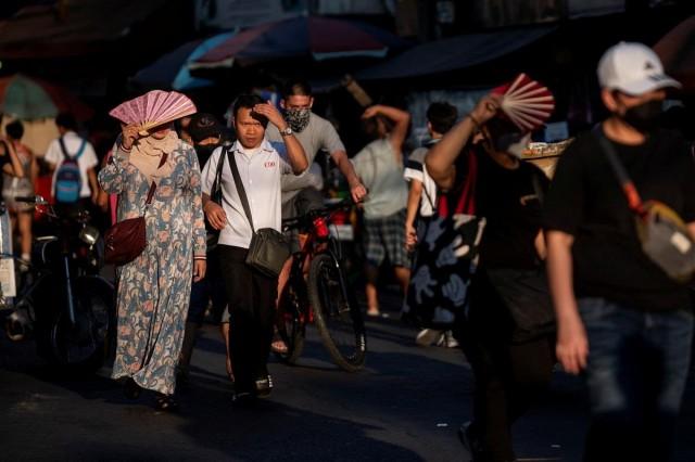 People shield their faces from the sun during a hot day in Manila, April 19, 2024. REUTERS/ Lisa Marie David