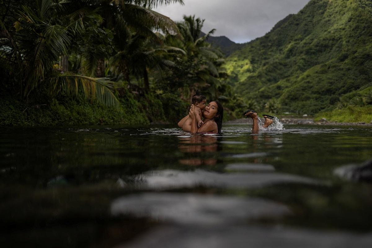 Uratua holds six-month-old Kiana as they play inside a freshwater stream in Teahupo'o, Tahiti, French Polynesia, August 3, 2024. REUTERS/ Carlos Barria