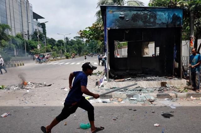 A demonstrator runs next to a vandalized police box during a protest demanding the stepping down of Bangladeshi Prime Minister Sheikh Hasina, following quota reform protests by students, in Dhaka, Bangladesh, August 4, 2024. REUTERS/ Mohammad Ponir Hossain