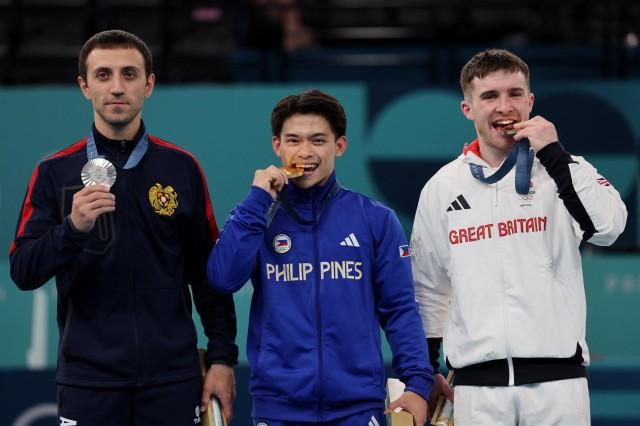Paris 2024 Olympics -Gold medalist Carlos Yulo of Philippines celebrates on the podium with silver medallist Artur Davtyan of Armenia and bronze medallist Harry Hepworth of Britain. REUTERS/Mike Blake
