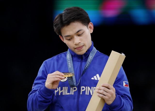 Paris 2024 Olympics - Artistic Gymnastics - Men's Vault Victory Ceremony -  August 04, 2024. Gold medalist Carlos Yulo of Philippines looks at his medal on the podium. REUTERS/Amanda Perobelli