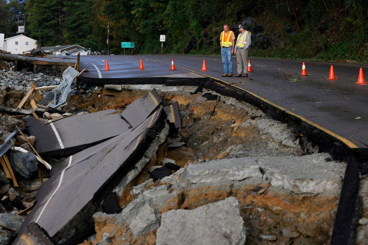 Workers survey large section of highway washed away by Tropical Storm Helene in Boone, North Carolina